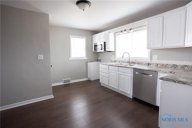 kitchen featuring baseboards, stainless steel appliances, dark wood-style floors, white cabinetry, and a sink