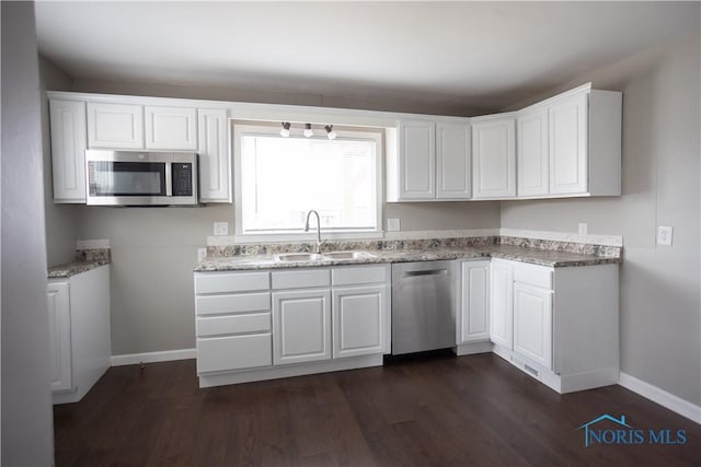 kitchen with dark wood-style flooring, white cabinets, stainless steel appliances, and a sink