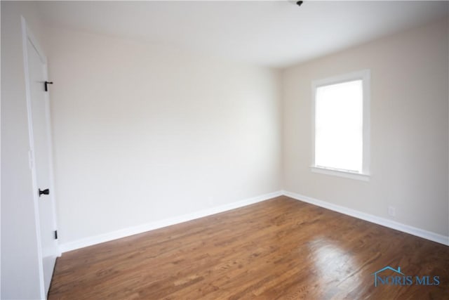 spare room featuring baseboards and wood finished floors