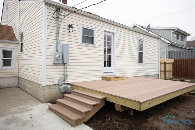 rear view of house with a wooden deck, a patio, and fence