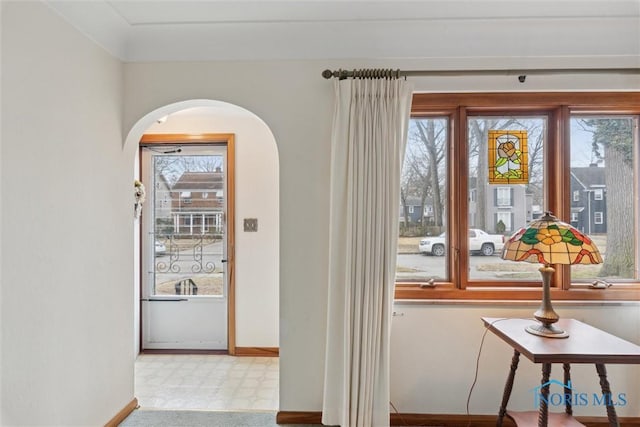 doorway with arched walkways, plenty of natural light, and baseboards