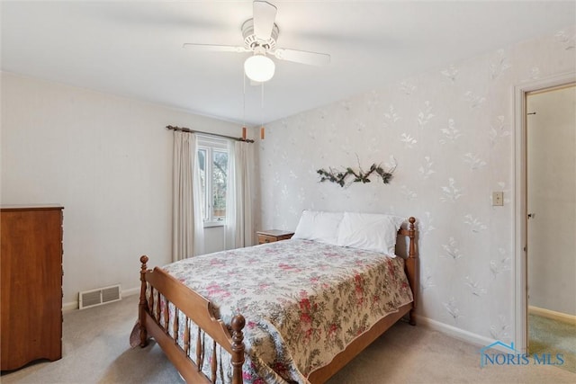 bedroom with carpet floors, visible vents, a ceiling fan, baseboards, and wallpapered walls