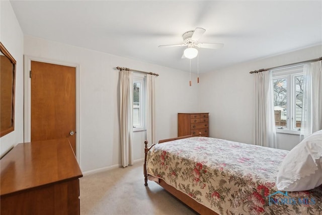 bedroom featuring light carpet, ceiling fan, multiple windows, and baseboards