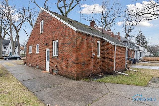 view of home's exterior with a chimney, a residential view, and brick siding