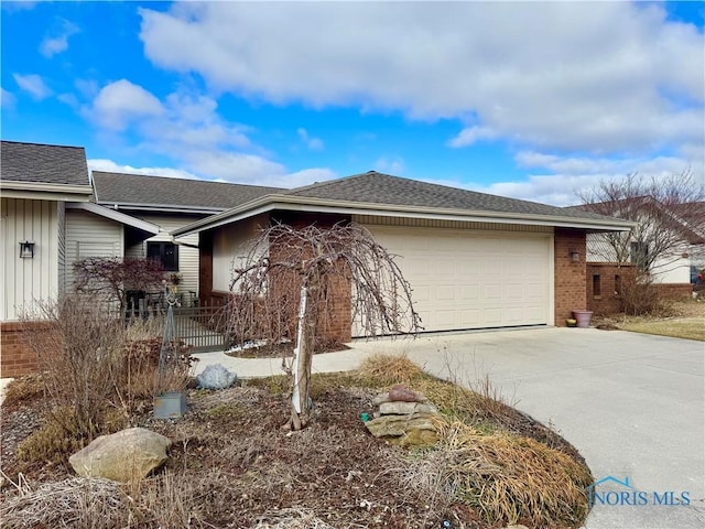 view of side of property with a garage, a shingled roof, concrete driveway, and brick siding