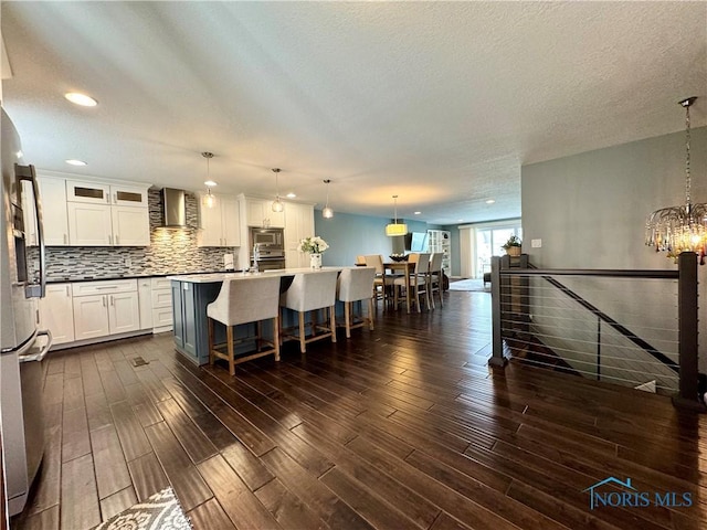 kitchen featuring appliances with stainless steel finishes, backsplash, dark wood-type flooring, and wall chimney range hood