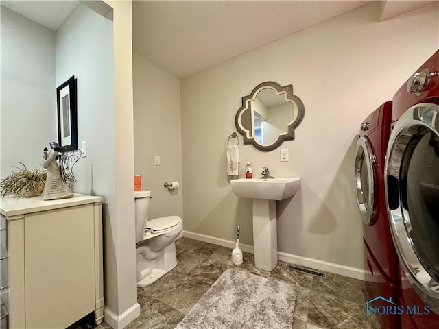 bathroom with toilet, baseboards, visible vents, and washing machine and clothes dryer