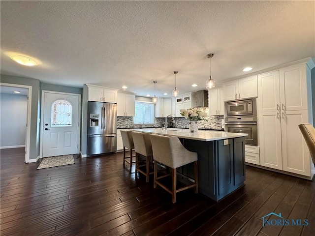 kitchen featuring dark wood-style flooring, stainless steel appliances, tasteful backsplash, white cabinets, and a sink