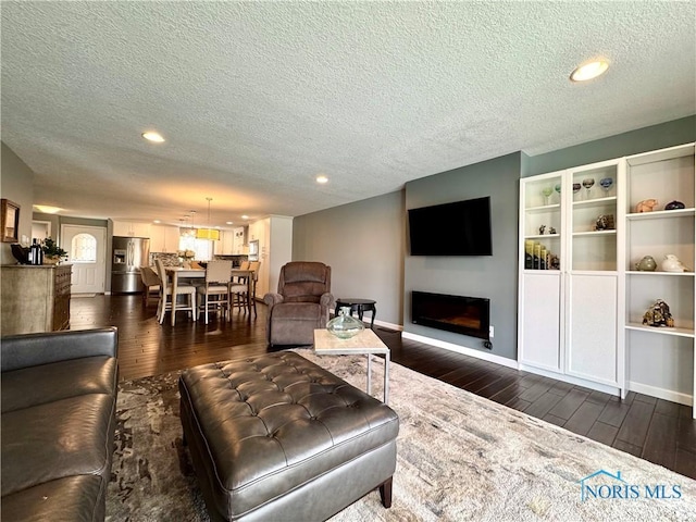 living room featuring a textured ceiling, a fireplace, dark wood finished floors, and recessed lighting