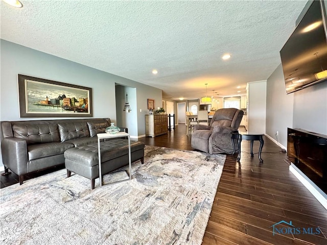 living room featuring dark wood-style floors, a textured ceiling, and baseboards