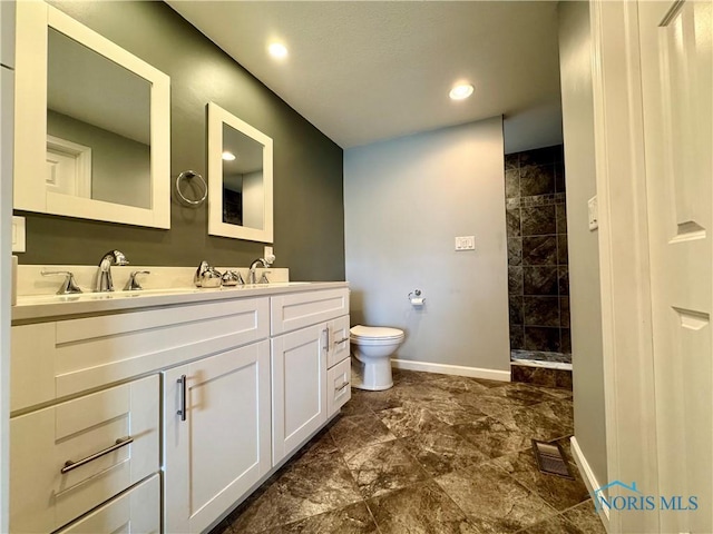 full bathroom featuring toilet, visible vents, baseboards, a tile shower, and double vanity