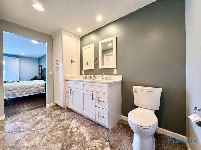 full bath featuring toilet, ensuite bath, baseboards, and a sink