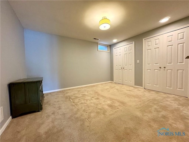 unfurnished bedroom featuring carpet floors, baseboards, visible vents, and two closets