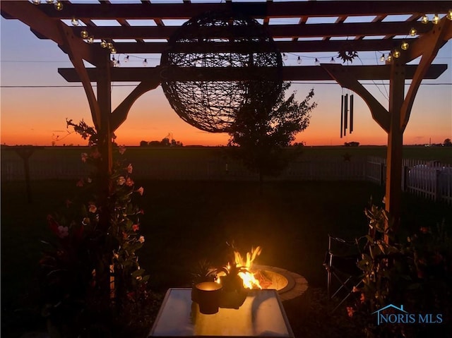 yard at dusk featuring an outdoor fire pit, fence, and a pergola