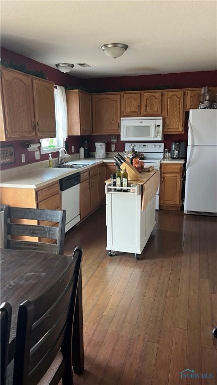 kitchen featuring white appliances, light countertops, a sink, and dark wood-style flooring