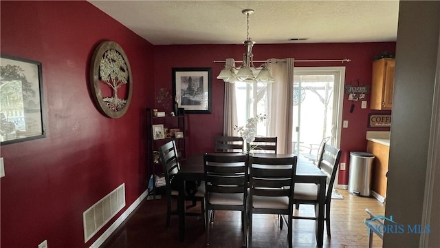 dining area featuring baseboards, light wood-type flooring, visible vents, and a notable chandelier