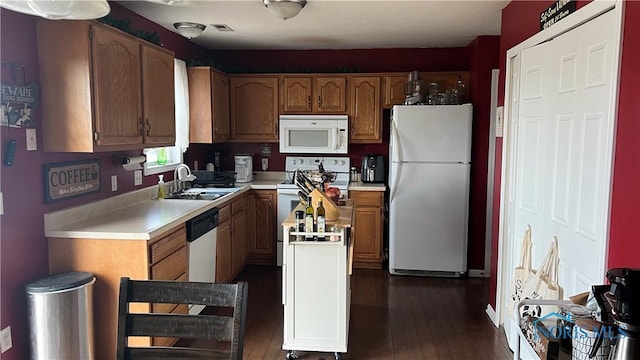 kitchen featuring white appliances, a sink, light countertops, brown cabinets, and dark wood finished floors