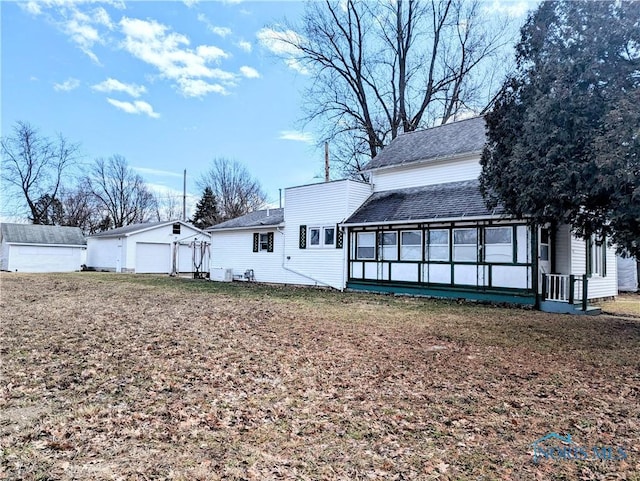 back of house featuring an outbuilding, a shingled roof, and a garage