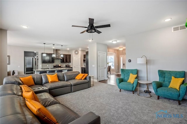 living area with a ceiling fan, baseboards, visible vents, and carpet flooring