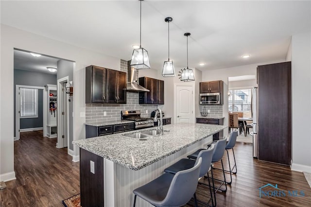 kitchen with decorative backsplash, appliances with stainless steel finishes, a kitchen breakfast bar, and a sink