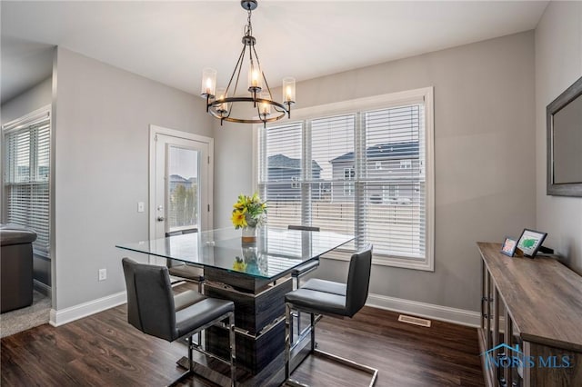 dining area with dark wood-style floors, a notable chandelier, and baseboards