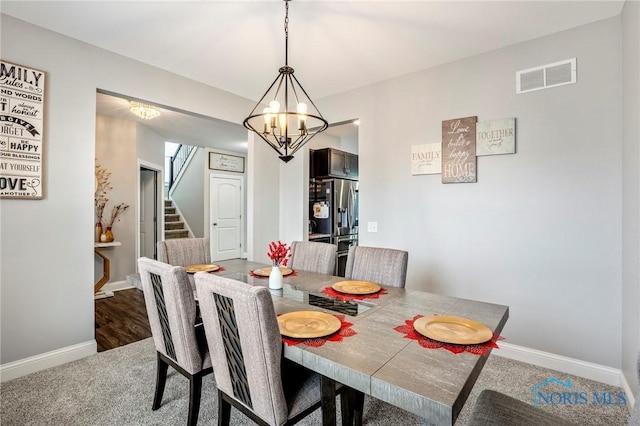 dining space featuring carpet flooring, visible vents, baseboards, stairway, and an inviting chandelier