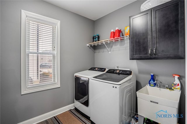 clothes washing area featuring cabinet space, a sink, baseboards, and separate washer and dryer