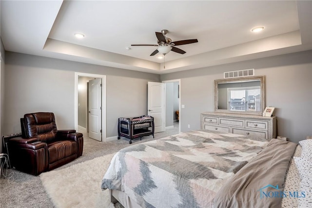 bedroom featuring baseboards, visible vents, a raised ceiling, and light colored carpet