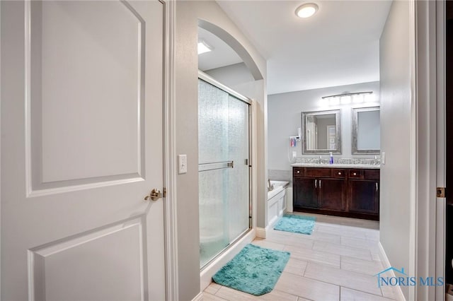 bathroom with a stall shower, a bath, and double vanity