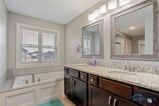 bathroom featuring a bath, a wealth of natural light, and a sink