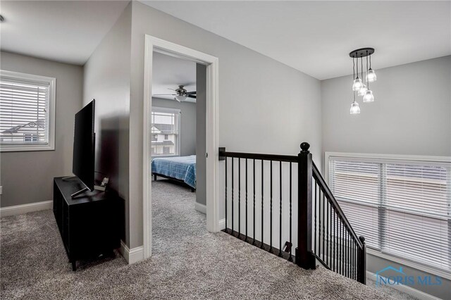 hallway with an upstairs landing, carpet flooring, and baseboards