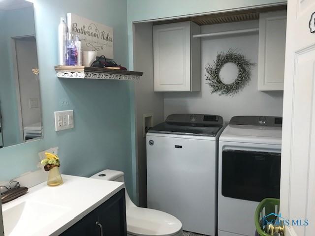 laundry area with separate washer and dryer, a sink, and cabinet space