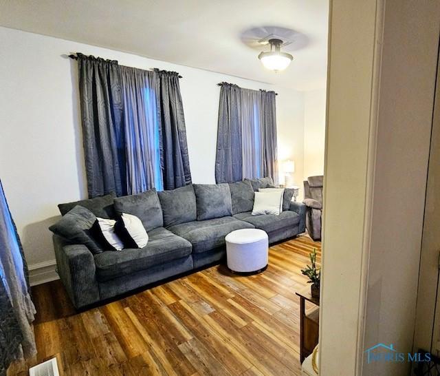 living area featuring visible vents and wood finished floors