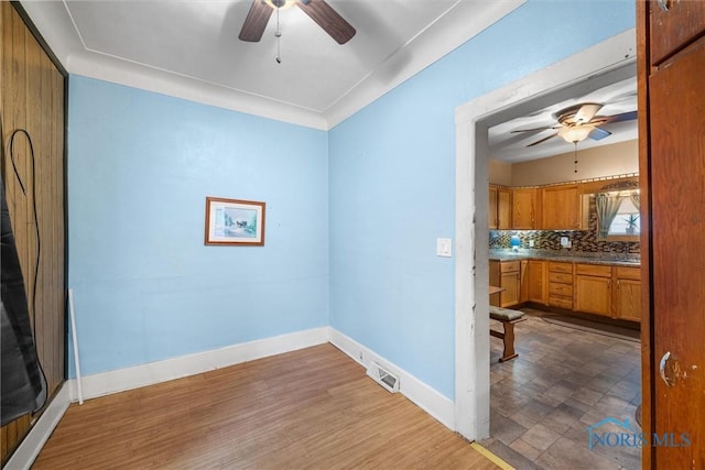 empty room featuring baseboards, visible vents, ceiling fan, and wood finished floors