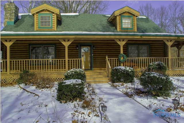 log-style house with a porch, a shingled roof, and a chimney