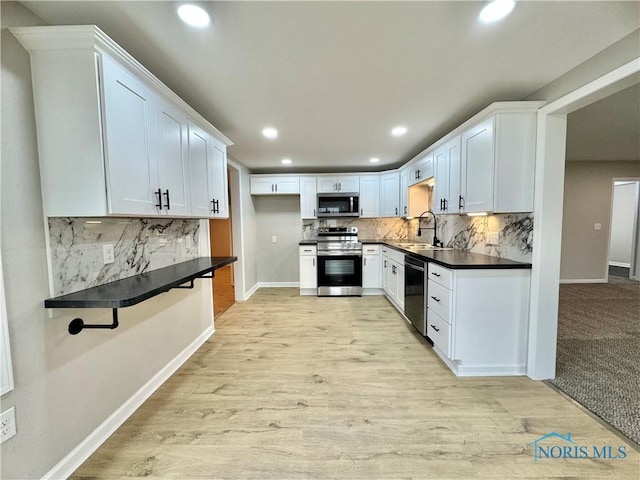 kitchen with appliances with stainless steel finishes, dark countertops, a sink, and tasteful backsplash