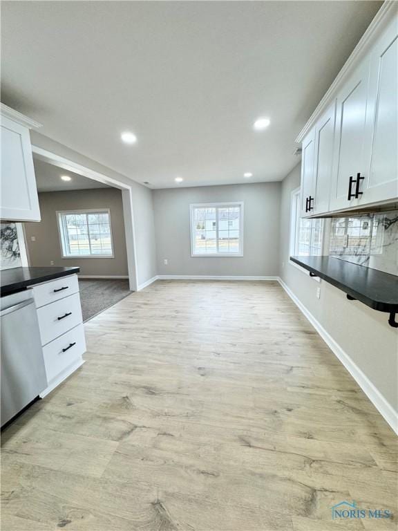 kitchen with dark countertops, a healthy amount of sunlight, light wood-style flooring, and dishwasher