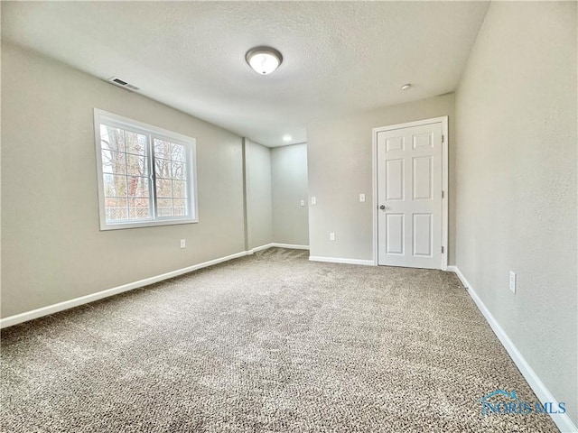 carpeted empty room with visible vents, a textured ceiling, and baseboards