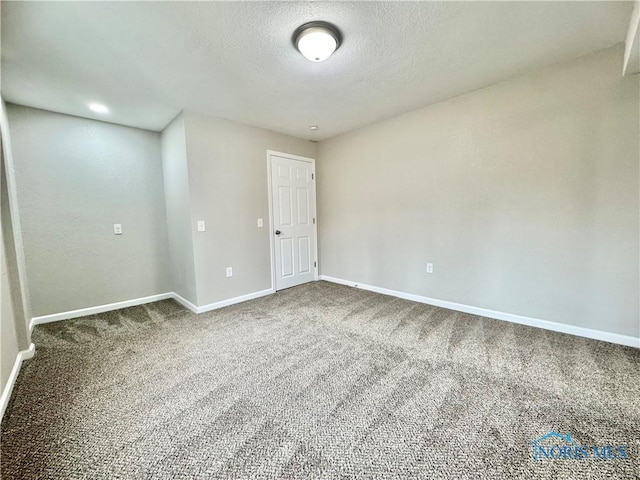 carpeted empty room featuring baseboards and a textured ceiling