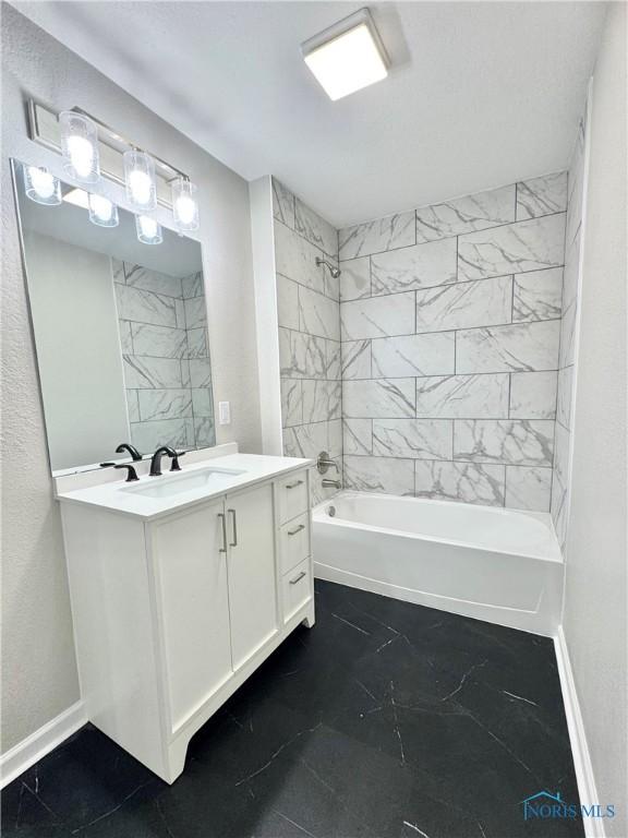 bathroom featuring bathtub / shower combination, vanity, and baseboards