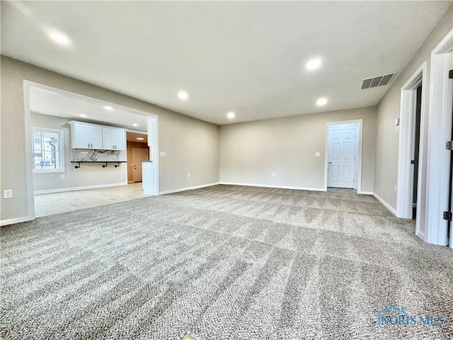 unfurnished living room featuring light carpet, baseboards, visible vents, and recessed lighting