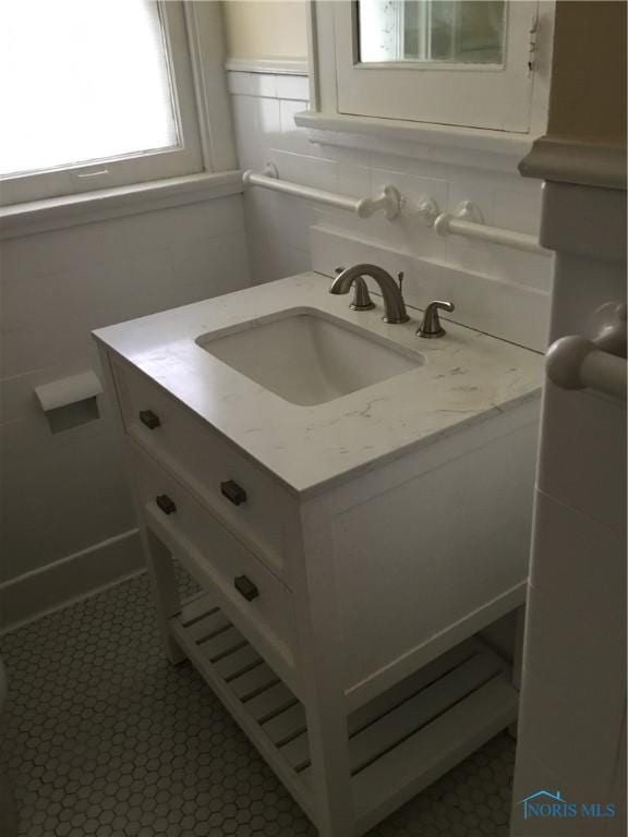 interior space featuring tile patterned flooring, backsplash, vanity, and tile walls