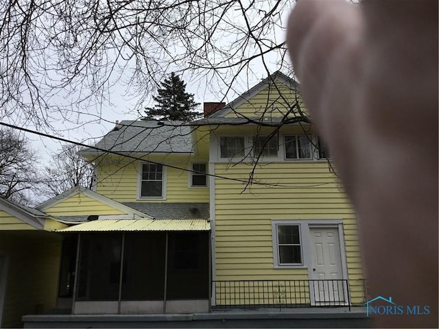 view of property exterior featuring a sunroom and a chimney