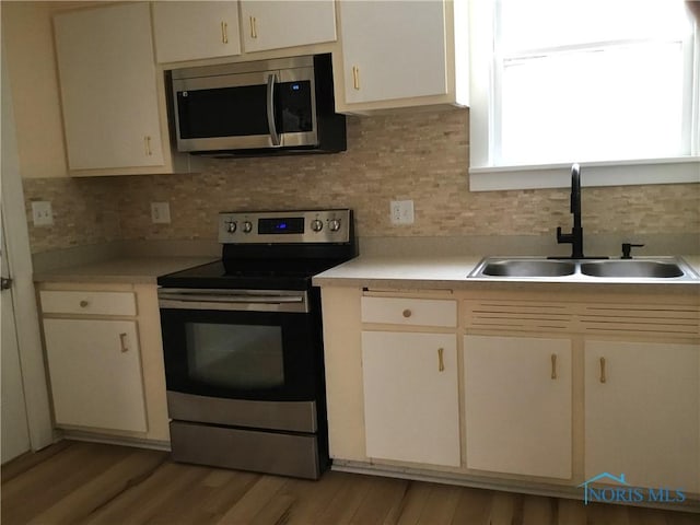 kitchen with tasteful backsplash, appliances with stainless steel finishes, light countertops, and a sink