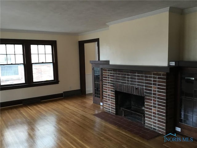 unfurnished living room with baseboards, ornamental molding, a tiled fireplace, and wood finished floors