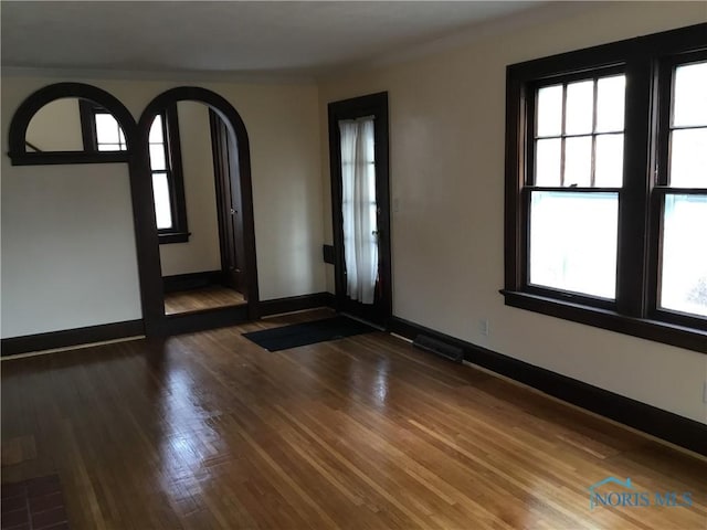 empty room featuring wood finished floors, visible vents, and baseboards