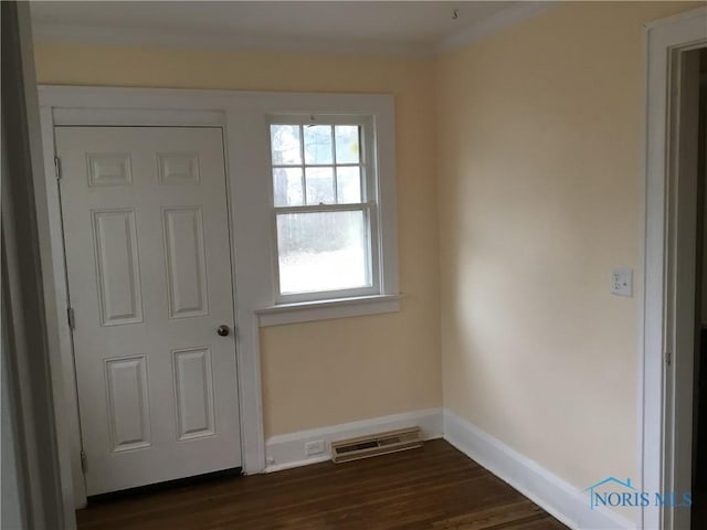 entryway with baseboards, visible vents, dark wood-type flooring, and ornamental molding