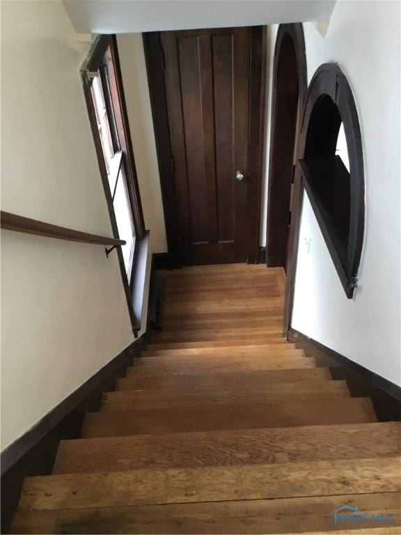 staircase with baseboards and wood finished floors