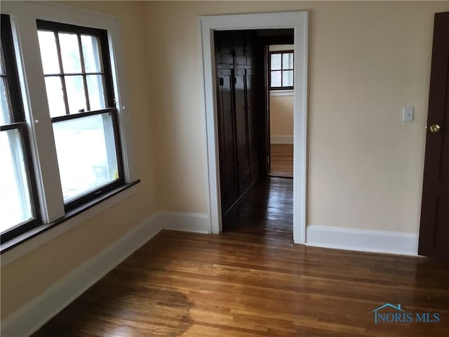 empty room with baseboards, a wealth of natural light, and wood finished floors