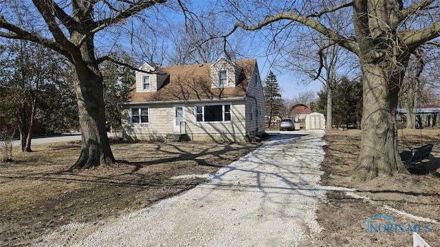 new england style home featuring an outbuilding and driveway